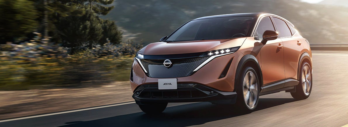 Nissan Ariya running on highway surrounded by grass and trees